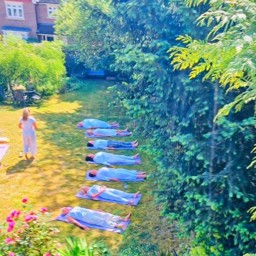 A group resting in savasana in the garden